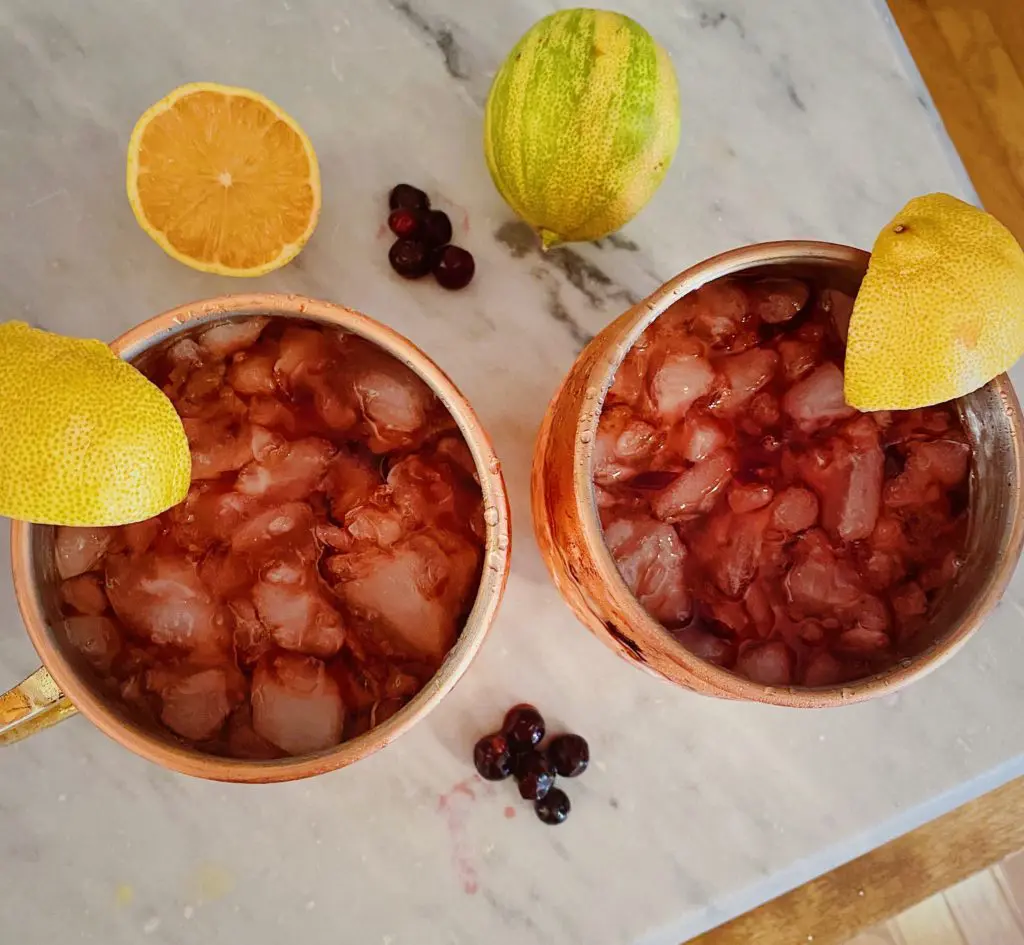 Top down shot of summertime huckleberry lemon smash cocktails in copper mugs