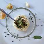 Glass bowl photographed from above with a sprinkle of sage and black pepper on garlic aioli