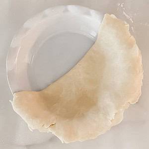 foolproof pie crust half unfolded in a white ceramic pie tin