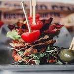 crispy bacon stacked with cherry tomato and greens on garlic baguette crisps