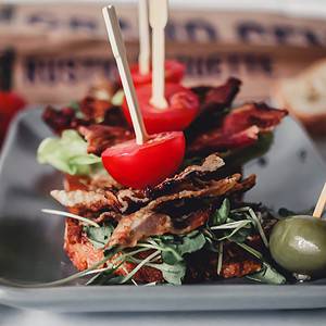 crispy bacon stacked with cherry tomato and greens on garlic baguette crisps