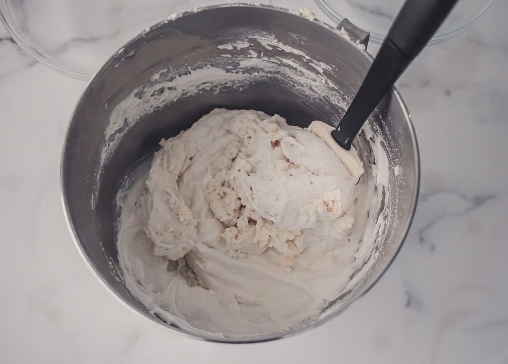 stage of mixing macaron batter by hand with rubber scraper