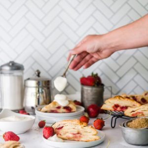 Beautiful shot of cream being spooned onto flaky and fresh berry scones by food photographer Kate O'Brien