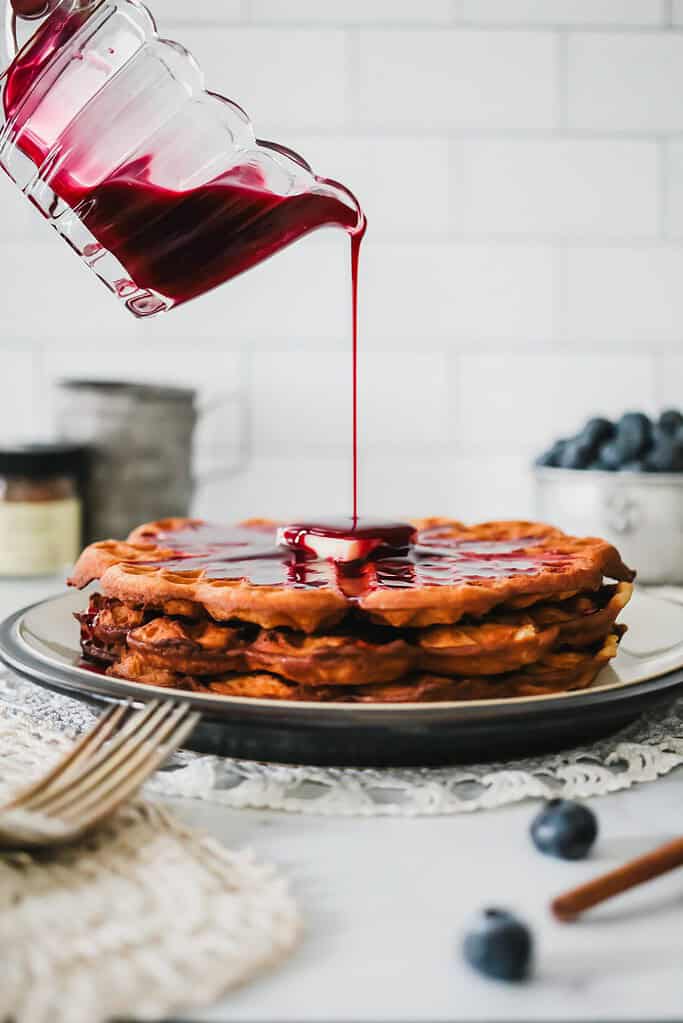 beautiful photo of berry syrup being drizzled on crispy cinnamon waffles. Shot by food photographer Kate