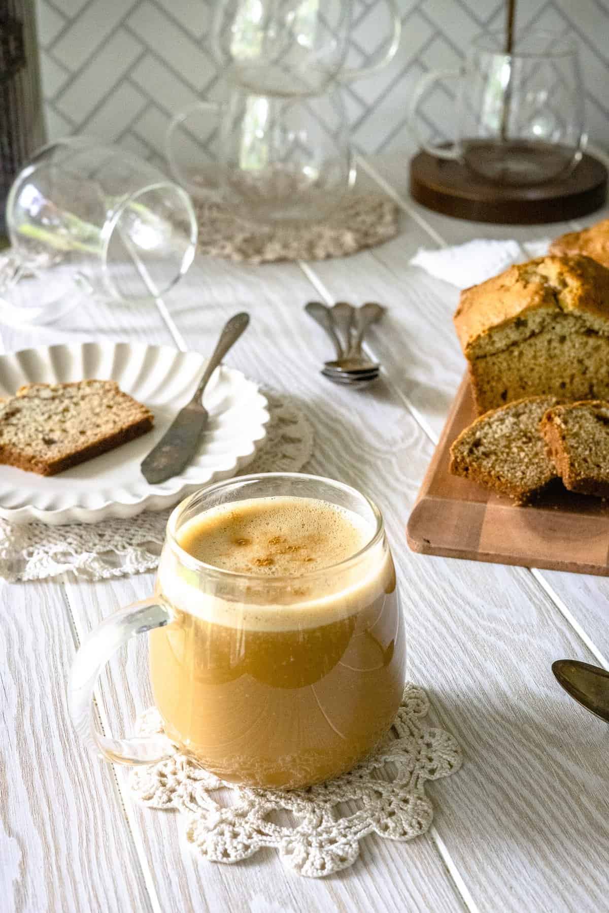 Banana Bread latte in clear glass cup with banana bread in background