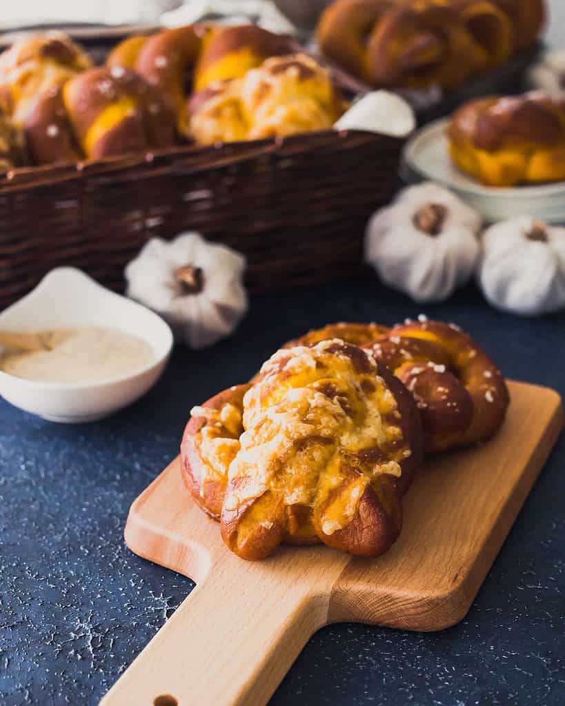 baked pumpkin pretzels on a wooden board with dip